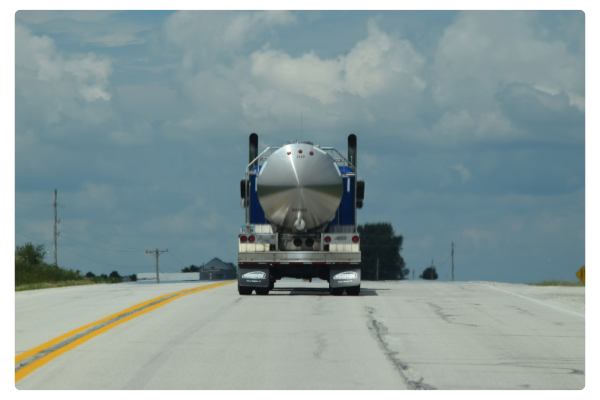 Photo of the back of a semi-truck tanker driving down highway